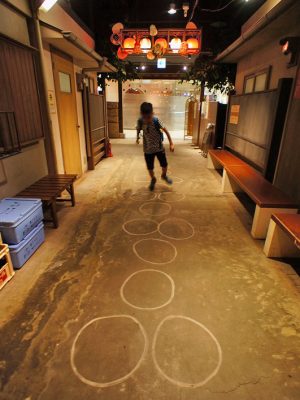 ▲遊びの小路の路上に描かれたけんけんぱで中国人観光客の男の子が楽しそうに遊んでいた。「こういう子どもの遊びは万国共通なんですね。特に解説をしているわけではないのですが、外国人のお子様もこの落書きを見ると自然にリズムをとって遊べるようです」と河村さん