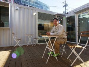 木材加工・流通・建築工事請負・製造販売を行う向井木材株式会社企画室長であり、木材コーディネーターの肩書を持つ【ウッディーラー豊田】会長・樋口真明さん/木材コーディネートを行った豊田市駅前のまちの案内所&ソフトクリーム店『エヌロク』ウッドデッキにて