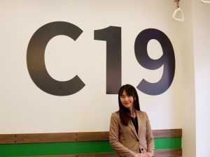 お話をうかがった、株式会社ハウスプラザの渡丸優生さん。壁の「C19」は東京メトロの駅ナンバリングによる綾瀬駅の表記。「予想以上の需要に手応えを感じています。『むすべや』を利用した方、地域の方、また私たちと、様々なつながりが生まれることを願っています」