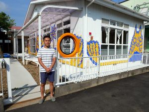 お話をきかせていただいた羽広さん。写実的な鉛筆画家としての顔ももち、同施設では羽広さんの絵画教室も開催されている。バックに少し写っているのは、海外アーティストのピーランダー・イエロー氏を招き、子どもたちと描いた壁画(筆者撮影)