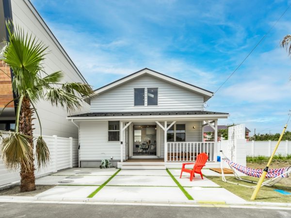 青空に映えるサーファーズハウス。</br>レジデンス全戸に花ブロックとパームツリーをセットして、外構を美しく統一感のあるものにしている