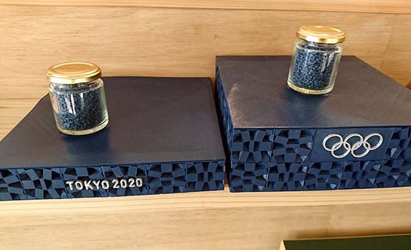 「みんなの表彰台プロジェクト」では、洗剤の詰め替えボトルをリサイクルして使用。プラスチックは溶かして東京五輪カラーに着色したペレット(瓶の中)になり、これを3Dプリンタ利用でデザインされたパネルに成形される