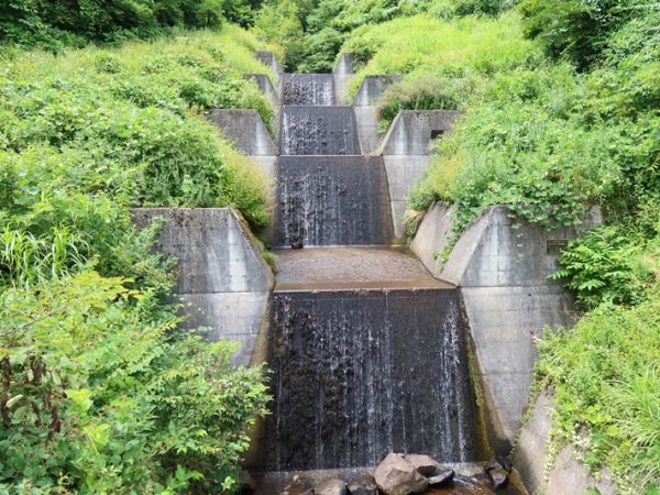 砂防堰堤といわれても想像できないという方のためにまずは見ていただこう。こちらは栂池沢第3号砂防堰堤。斜面に左右178mのコンクリートの塊が作られている。8年かけて作られたものだ