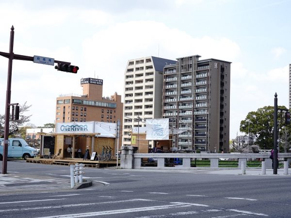 河川敷から見た殿橋テラス。かわまちづくりの始動にあたり、“水都”といわれる大阪市で水辺のプロジェクトを多数手がけていた有限会社ハートビートプランの代表・泉英明氏を勉強会に招いた。殿橋の橋詰を訪れた泉氏から、川だけでなく岡崎城も見える景観のよい場所を活かし、かわまちづくりの拠点を作るといいのではと提案を受けたのが殿橋テラスのはじまり。社会実験のときは単管足場を組んだデッキスペースのような仮設だったが、2021年にコンクリート製のしっかりとした空間に再整備された