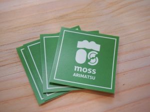 moss ARIMATSUのロゴマーク。右下は屋根の下で人と人が向き合ってるようにも見える。多くの意味を盛り込んだ