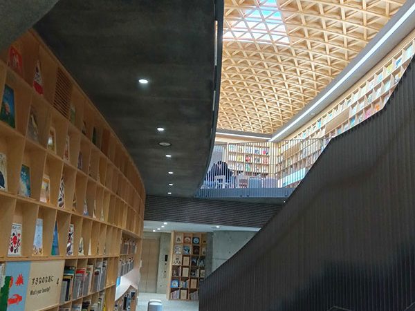 蝶を施したロゴマークの横に立つのは施設の案内をしていただいた「こども本の森 熊本」の主任主事・坂口沙采さん