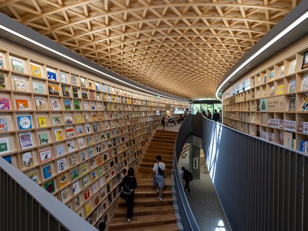 蝶を施したロゴマークの横に立つのは施設の案内をしていただいた「こども本の森 熊本」の主任主事・坂口沙采さん