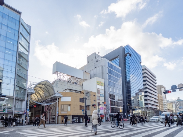 本通交差点から見た本通商店街の再開発対象エリア北側の様子。手前のガラス張り建物が「明治安田生命広島本通ビル」、その左側の灰色の建物が銀泉広島ビル」(2025年12月撮影)