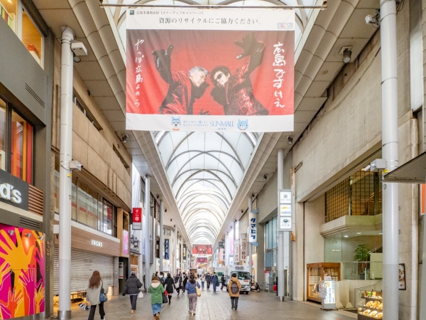 本通交差点から見た本通商店街の再開発対象エリア北側の様子。手前のガラス張り建物が「明治安田生命広島本通ビル」、その左側の灰色の建物が銀泉広島ビル」(2025年12月撮影)