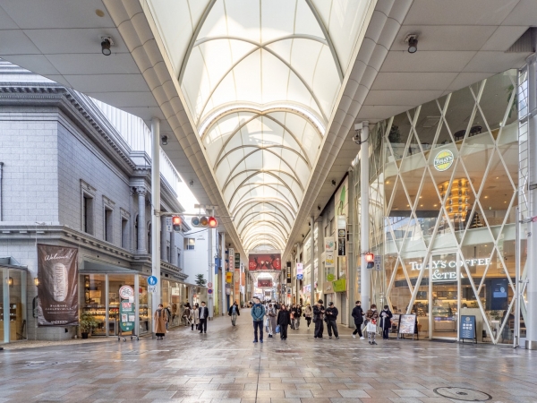 本通交差点から見た本通商店街の再開発対象エリア北側の様子。手前のガラス張り建物が「明治安田生命広島本通ビル」、その左側の灰色の建物が銀泉広島ビル」(2025年12月撮影)