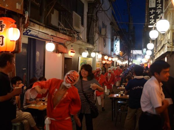 路地に出されたテーブルの間をひょっとこが練り歩く、なんとも楽しい夜遊びイベント