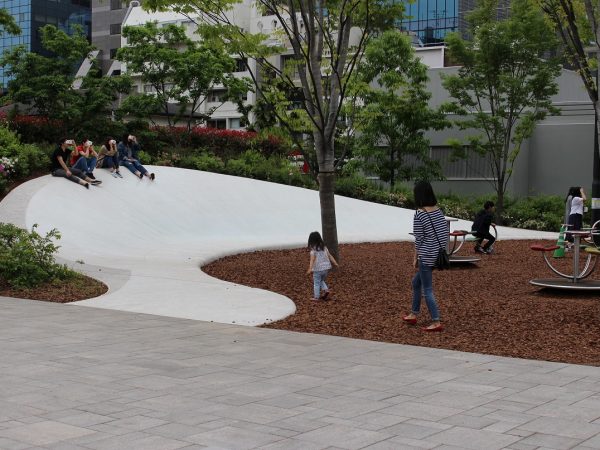 小山に見立てた曲線の滑り台。ベンチがわりにする人も