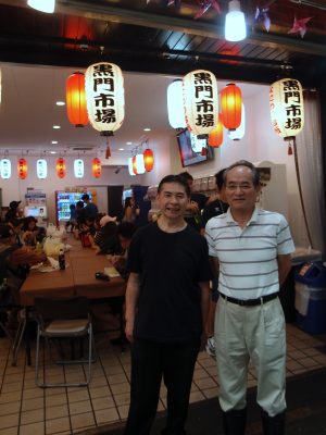 外国人観光客向けの無料休憩所『黒門インフォメーションセンター』前にて。黒門市場商店街振興組合の理事長・山本 善規さん（右）、副理事長・吉田 清純さん（左）