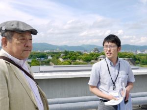 本館屋上には、竣工当時屋上庭園があったそうだ。写真左は山田孝延さん、右は案内してくれた岡山県建築指導課主任の川内秀治さん。背後に岡山城が見える。