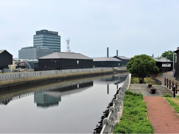 半田運河沿いに建つ、ミツカンの蔵や工場跡地。それぞれの建物にはミツカンマークが描かれている。左側奥に見える高いビルが、ミツカン本社
