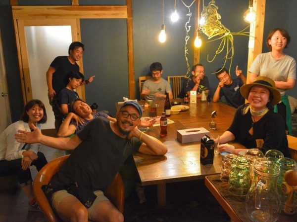 スナックでのひとコマ。「阿蘇び心」阿蘇店から引き揚げてきた思い出のテーブルを囲んで宿泊者と楽しそうに寛ぐスタッフたち