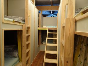 写真は、女性専用の相部屋。無垢の木をふんだんに使った居心地良さそうな空間。相部屋は3800円、個室＆半個室は4500円（チェックインは16時～22時）