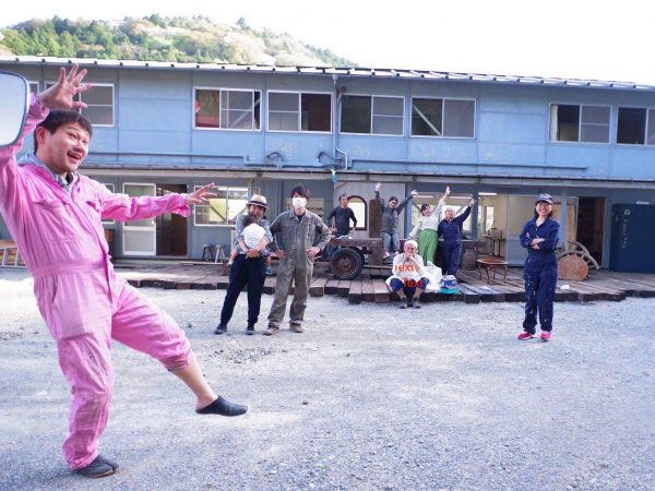 葉山ファクトリーの建物と参加者の人たち。ピンクのつなぎを着ているのがリーダーの加藤太一氏
