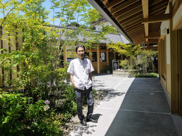 クラシキクラフトワークビレッジの中庭広場に立つ楢村さん。魅力的な路地を設けることで、街道から敷地の奥まで人の流れを呼び込んだ