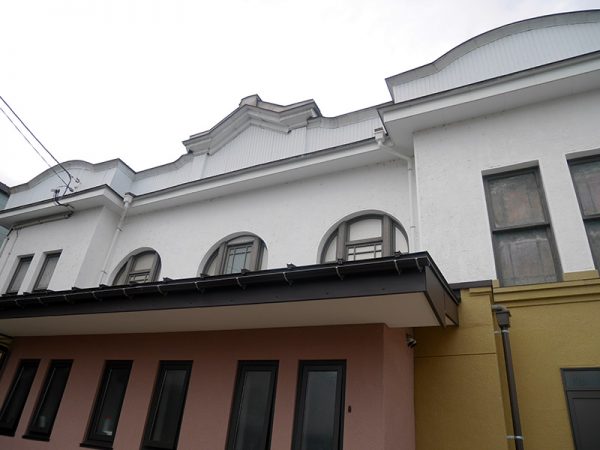 高田世界館の外観。正面から見る外壁はペンキが塗り直されているが、駐車場側はトタン壁になっている