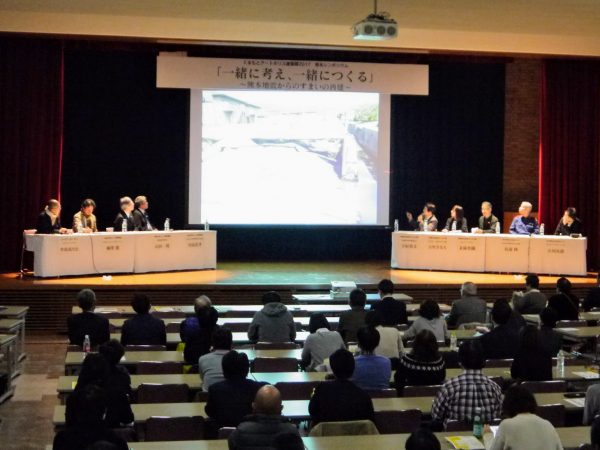 登壇者は左から、KAPアドバイザーの曽我部昌史氏、KAPプロジェクト「大腸肛門病センター高野病院」設計者の柳澤潤氏、病院長・山田一隆氏、設計者・川島浩孝氏、「阿蘇内牧温泉みんなの家」の阿蘇温泉病院病院長・下村貴文氏、設計者代表の古里さなえ氏、KAPアドバイザー・末廣香織氏、「熊本県総合防災航空センター」熊本県危機管理防災企画監・有浦隆氏、設計者の小川次郎氏