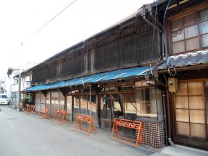 屋根の瓦も落ちて雨漏りもひどかったことから、ブルーシートで覆われた改修前の『やなぎ屋』。内部には元住人の生活道具が一式残っていたため、撤去に2週間近くかかったという。重伝建地区のため、外観はまちなみに揃え元の趣を残すよう配慮された