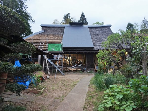 雨漏りによって、屋根の中央部にトタンで応急処置。4月に遂に茅の修繕が始まり、左正面のみ工事
