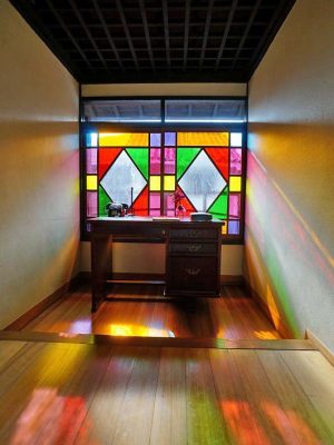 ▲2階廊下にあるレトロなステンドグラスは、もともとこの建物にあったものではなく、宮崎監督のデザイン画を元にして昔ながらの手延べガラスで再現されたもの。「監督の意見も取り入れているので、時代考証からいくと多少ズレる部分もあるんですが、本物の技術で本物を再現すれば、ちょっとした時代の違いがあっても、その建物は生き還ると思います。安普請でカタチだけ直すというのはいちばんダメ。その時代、その時代のちゃんとしたものを作れば、今後も建物は残されていくと私は考えています」と松居さん