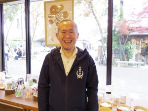 （一社）阿蘇門前町商店街振興協会理事の岩永さん。老舗文具店を営む丹波屋さんでは、和風小物や水に浮かべると文字が浮き出る「御紙水みくじ」が人気だそう（写真：山口）