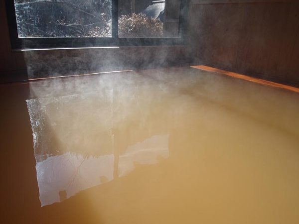 ヒノキ造りの浴槽に満たされた黄金色の温泉