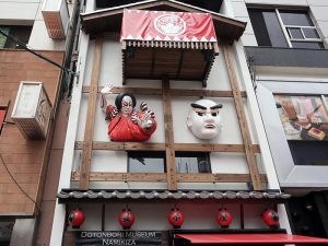 道頓堀ミュージアム並木太鼓櫓の下では、歌舞伎の狐忠信がにらみをきかせ、文楽人形の文七が眉を上げ下げしている
