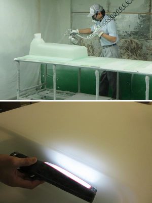 上：硬化した透明のクリスタルカウンターとシンクの裏側から塗装を吹き付けている様子。人気色はクリスタルスノー。まるで本物のすりガラスのように見える
<BR>
下：クリスタルカウンターとシンクの結合部に光を当てて気泡が入っていないか検査をしている様子。こちらは検品見本であえて気泡を入れてあるのだが、筆者の肉眼では探し出すことはできなかった（共にTOTOプラテクノ株式会社勝浦工場にて撮影）