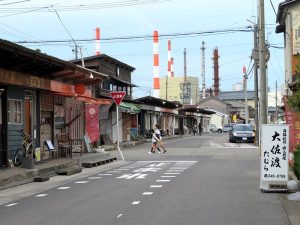 遠くに工場の煙突が見える沼垂テラス商店街。右手の店がこの商店街を生んだ高岡氏ら姉弟の実家である大衆割烹大佐渡たむら