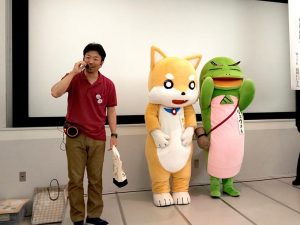 夏休みフェスタでは、博物館のキャラクターのカイト（左）とリュウさん（右）の着ぐるみも登場した。アテンド役は、お話を聞かせてくださった中尾智行さん