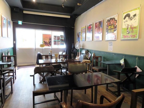 泪橋ホール店内。テーブルをどかせば40人は入る。映画上映時は入えい口側を閉めてスクリーンを作る。上映中に入ってくる人は脇のドアから背後に回る仕組み