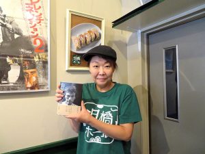 著書を手に多田氏。泪橋ホールの名物は丸善食堂以前に中華料理店をやっていたことから、多田氏のおかあさんが作る餃子なのだとか。取材時に食べ損ねたのが残念