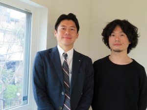 「広がる屋根」2階に設置されたトリプルガラスの入った樹脂窓の前で岩崎氏（左）、宇都宮氏