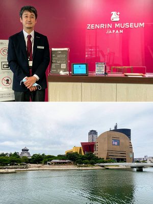 上：ゼンリンミュージアムのエントランスで、館長の佐藤渉さん。館名の上に描かれたシンボルマークは、地図を描いて丸めた羊皮紙と、方角を指し示す星と月がモチーフ。未知の土地を求めて航海する、船のイメージも重ねられている　</br>下：ゼンリンミュージアムのあるリバーウォーク北九州（写真右手）。建物の設計は、六本木ヒルズなども手掛けたアメリカの建築家ジョン･ジャーディ。写真左手には小倉城天守閣が見える