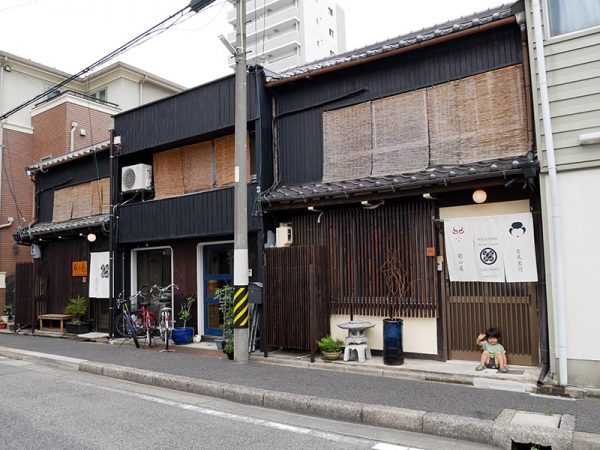 「駅西銀座通商店街」のメインストリートから1本入った場所にある「古民家宿 菊の屋」。手前が２年前にオープンした本館、中央は、現在は菊池さんの住まい、奥が昨年できた