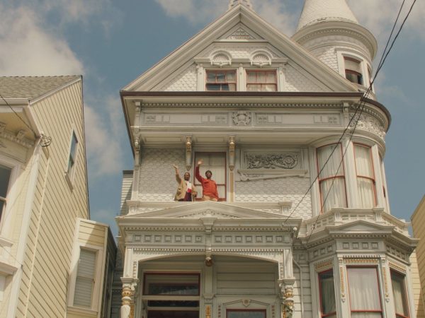 白いうろこ状の外壁に赤、金色がアクセントになった住宅、右手にある塔もかわいい