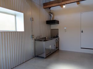 入り口から内部を見たところ。左手奥にキッチン、正面のドアは水回りに続くもので、帰宅後すぐに風呂場にということができる。右手が居住空間となる箱の壁