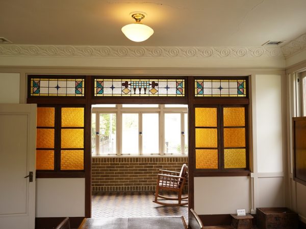 洋館の玄関に置かれたオリジナル家具。建物が建てられたときに合わせてオーダーされたもので、帽子かけやステッキ入れがあり、外国人のゲストが来たときに身支度をするのに使われた。上部の半円の真ん中に上下に延びる木は、鍵をモチーフにしたデザインが施されている