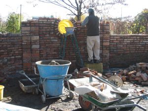 漬物の樽で窓をつくり、レンガの塀をつくる裕幸さん