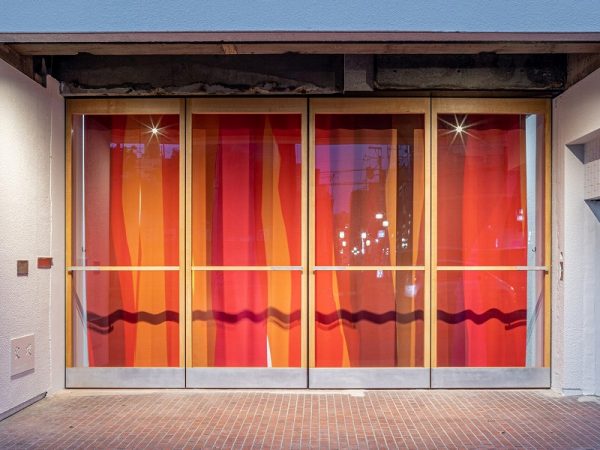 無機質な空間に温かみをもたらす、高さ280センチもの大型開き戸。家具職人（木枠）と構造家（金属補強）、アルミ作家（取っ手）、北村さん（設計）の4人がかりでつくり上げた。ドア枠をなくして躯体に直付けし、上下の2点だけで支えるという独自の構造でフルオープンが可能に