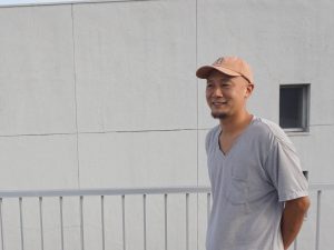 館内の案内や取り組みを説明してくださった幡野さん。住人からは親しみを込めて「ハタ坊」と呼ばれる。背景の屋上にある壁を活用して、プロジェクターで投影した映画鑑賞会も検討中だとか