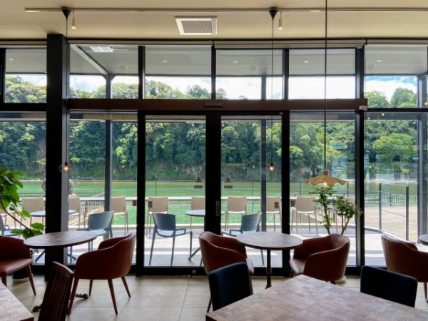 HASSENBA1階から球磨川を望む。屋内のカフェスペースから屋外のテラス席、川の流れ、対岸の緑と、視界が遠くまで抜けていく