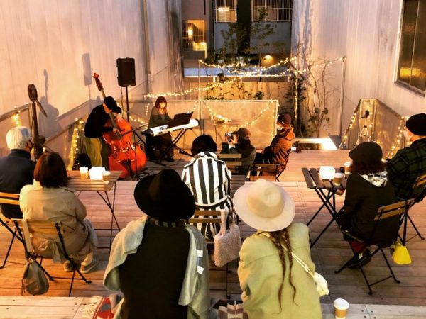 商店街から見たオモケンパーク。アーケードのビルの間にそこだけぽっかりと上空が見える。道路に接して建てると延焼防止のシャッターが必要になるため、前庭を設けて奥まった位置に建てた。通りに面して植栽し、緑の景観を提供する