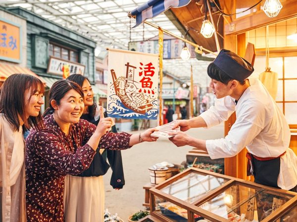 ▲園内へ足を踏み入れると、最初に広がるゾーンが1960年代の商店街の街並みをイメージした『夕日の丘商店街』だ。商店街の全長は約150ｍ。30店舗のうち15店舗は飲食や物販など体験型の実店舗。残る15店舗はパフォーマンスのステージや写真撮影ができるセットになっている。商店街の建物意匠については時代考証を重ね、当時の建築様式・生活様式を再現。厳密には1960年代の建物ではなく大正から昭和初期にかけてのレトロな建物となっているため、ホーロー看板など小道具の中にはすでに手に入らないアイテムも多く、わざわざ新たに製作したものも含まれている