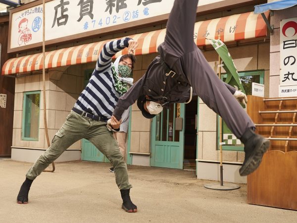 ▲昭和のドラマに出てきそうな典型的な“駐在さんと盗人”のパフォーマンス。商店街のお店や店主・住人達にはあらかじめ名前やキャラクターが設定されており、お節介でお人好しで人情味あふれる住人たちとのリアルな掛け合いが来場客を和ませる。こうした大小のパフォーマンスは一日に数回行われているが、臨場感を大切にするためあえて開催時間を予告していない。「お客様の様子を見ながら、住人たちが口上や絡みの内容を毎回変えています（広報担当者談）」