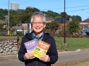 緑の国分寺崖線を背に真貝さん。新著を手にしていただいた